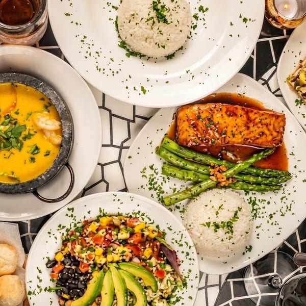 An overhead view of a table laden with various dishes, including salmon, soup, salad, and rice.