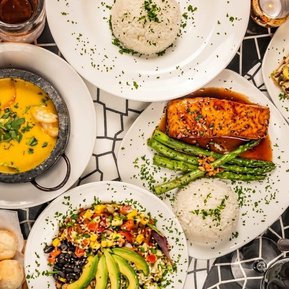 An overhead view of a table laden with various dishes, including salmon, soup, salad, and rice.
